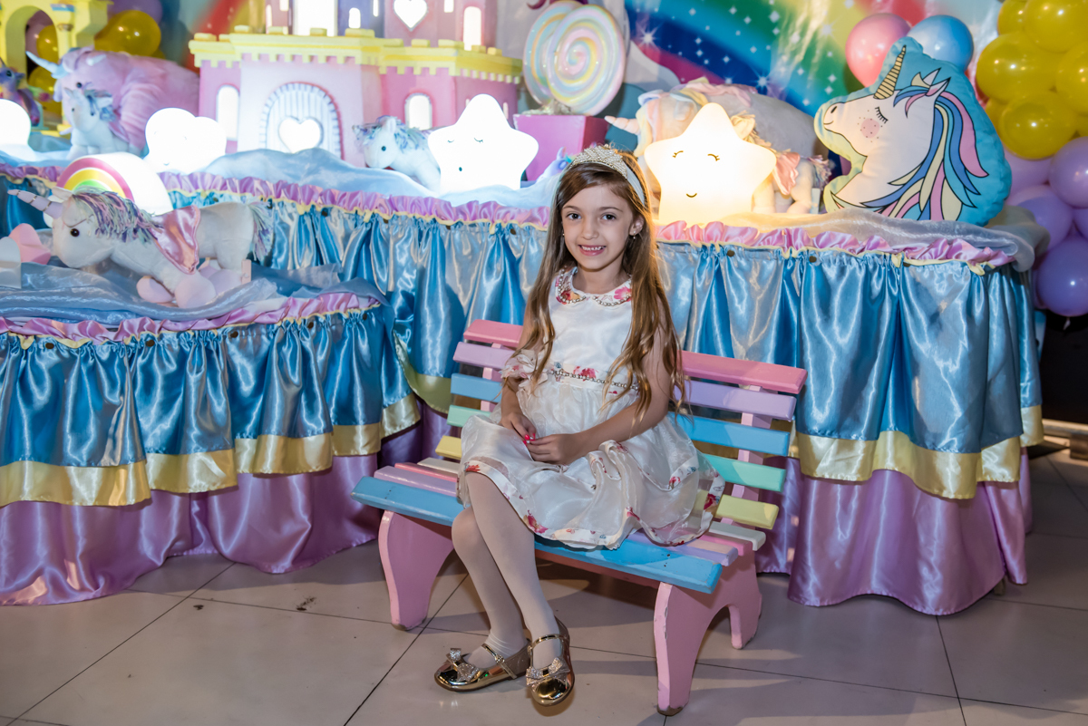 aniversariante senta e se diverte com a mesa do unicornio