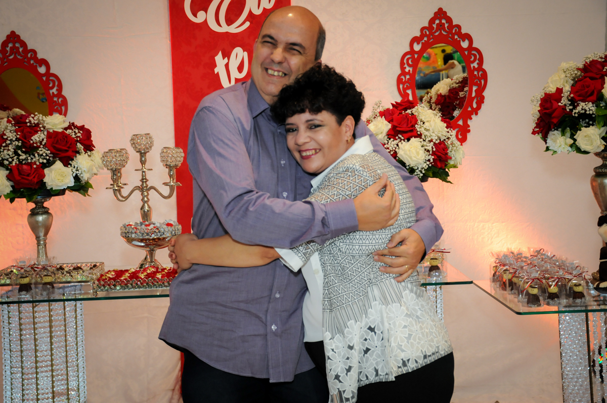 abraço do casal em frente a mesa decorada bodas de prata no Buffet Fábrica da Alegria, osasco, sp