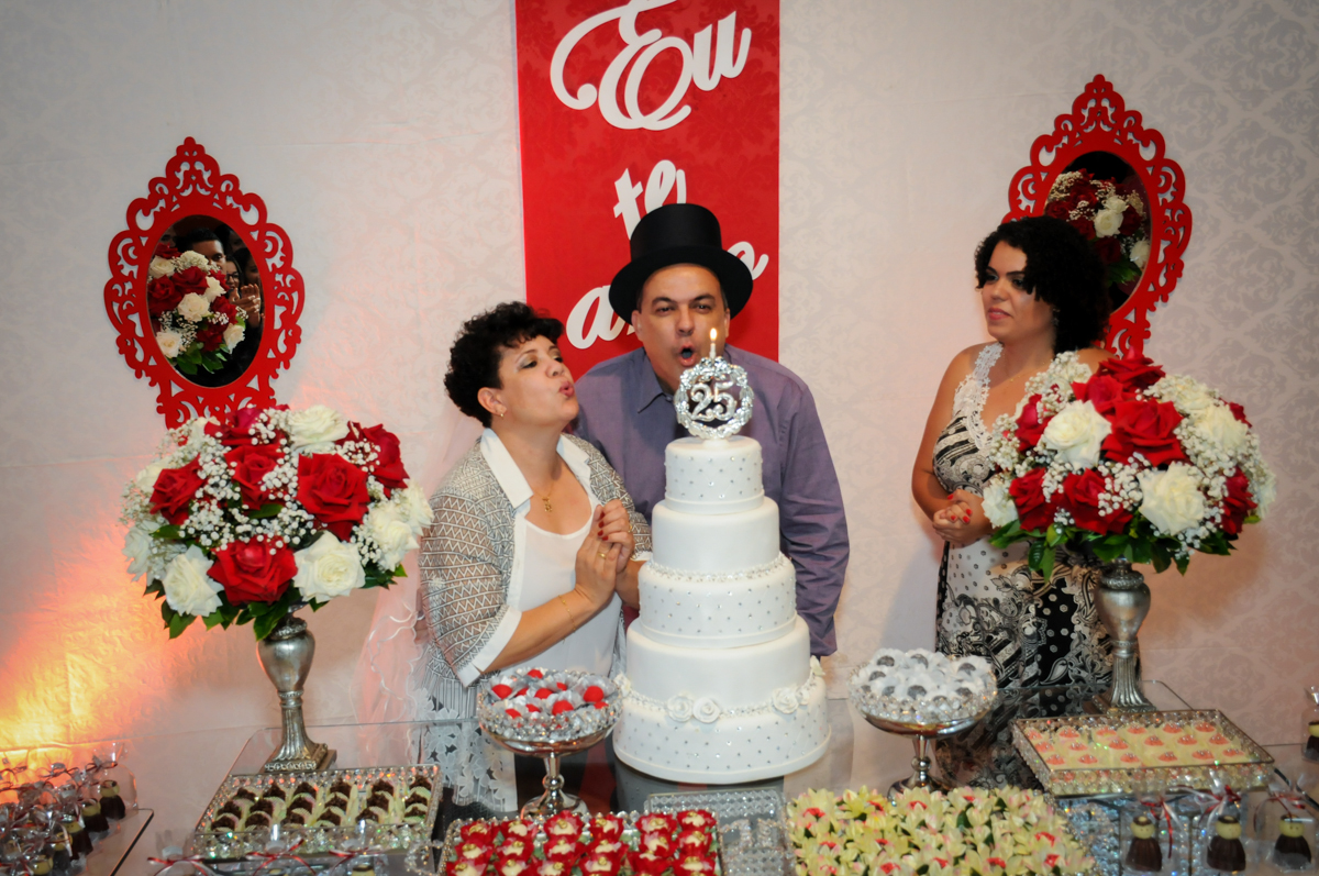 assoprando a velinha do bolo na festa de 25 anos de casados do casal no  Buffet Fábrica da Alegria, osasco, sp