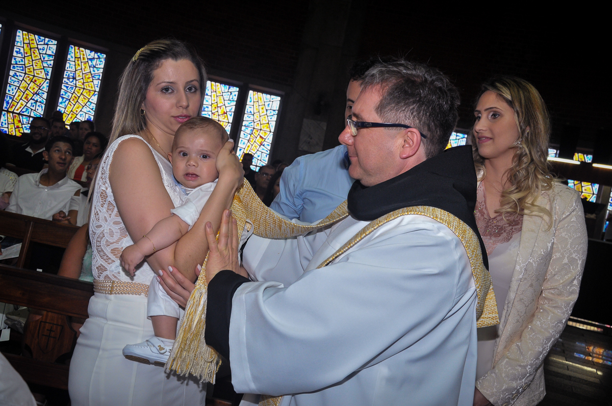 O padre faz o sinal da cruz no peito do Matheus no Paróquia São Bento Morumbi