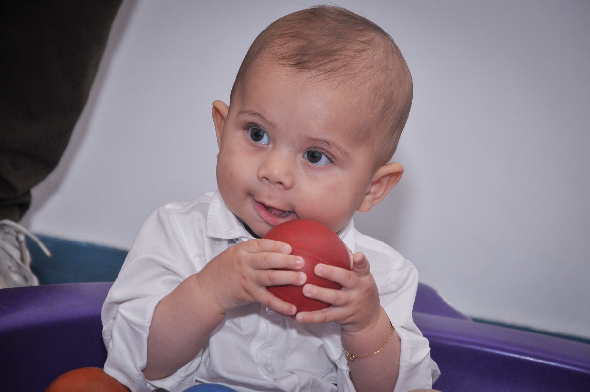 com uma bolinha na mão Matheus brinca em sua festa de batizado no festa no condomínio