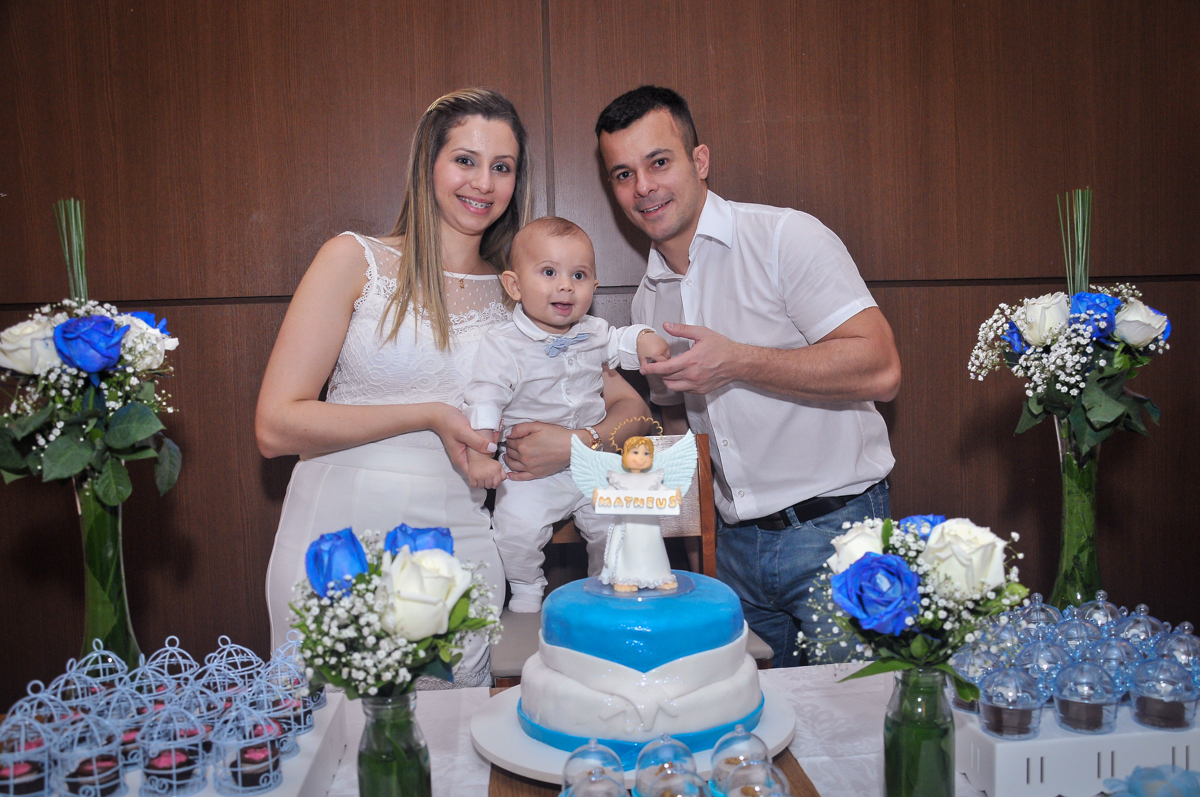 Matheus e seus pais na mesa decorada para a festa de batizado festa no condomínio