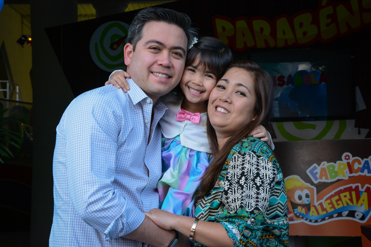 foto da aniversariante com seus pais em baixo do arco de bexigas no Buffet Fábrica da Alegria, Morumbi, SP