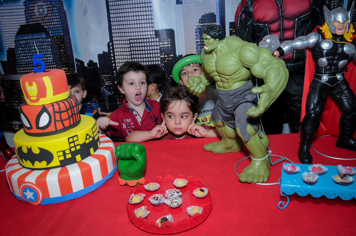 A criançada em frente a mesa decorada super heróis para cantar o parabéns no Buffet Fábrica da Alegria Morumbi