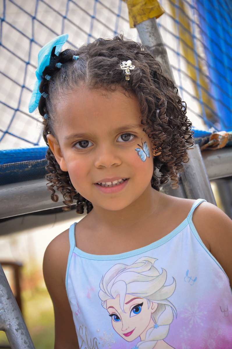 a aniversariante faz pintura de uma borboleta no Condomínio São Paulo, SP, tema da festa Frozen