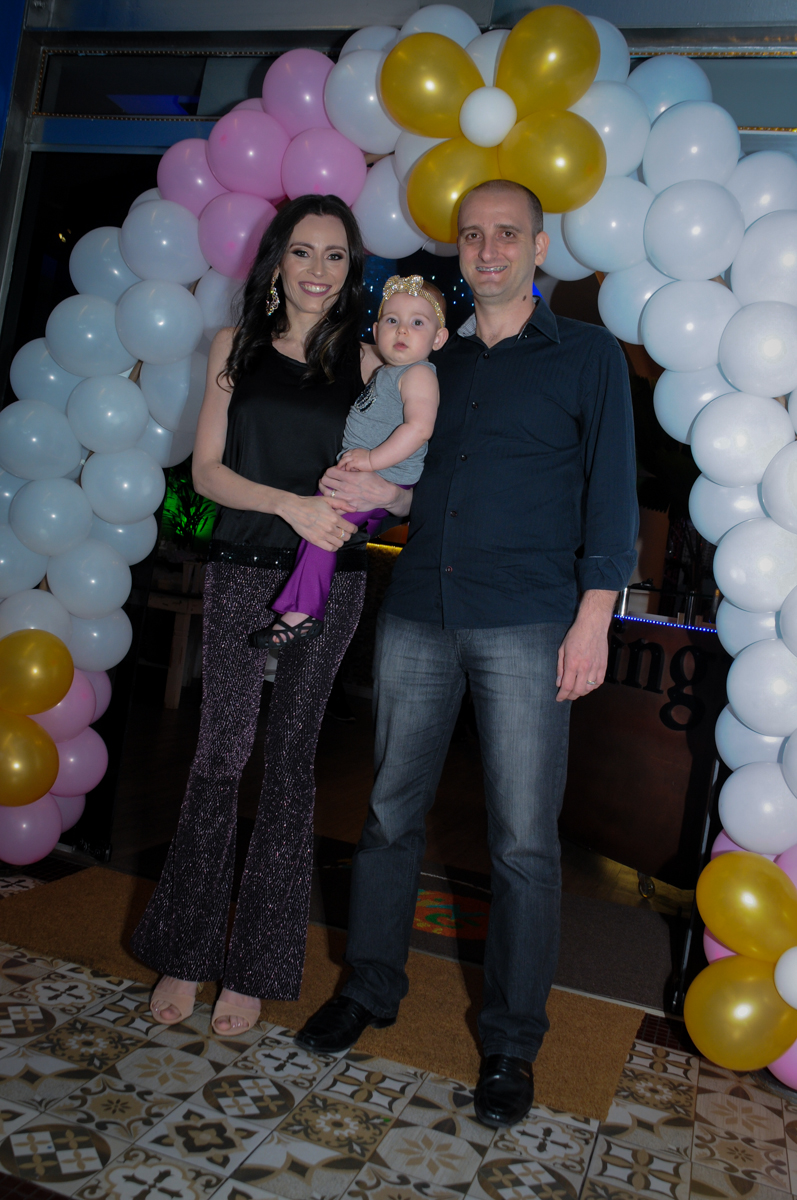 foto da aniversariante com seus pais embaixo do arco de bexigas no buffet amazing, alphaville,sp, tema da mesa bonecas princesas