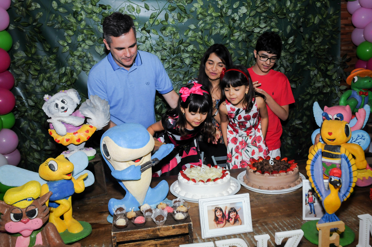 A família estão na mesa para cantar parabéns para as aniversariantes no