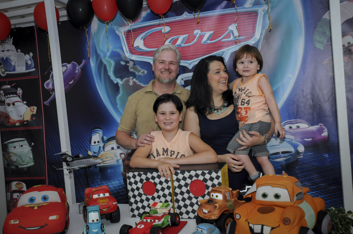 foto da família na mesa decorada no  buffet feliz da vida, festa infantil Théo 3 aninhos, tema da festa carros