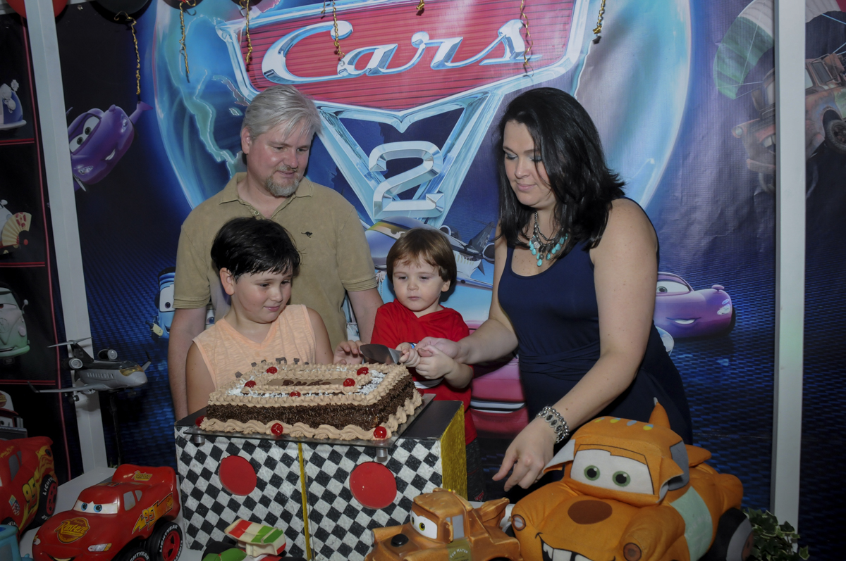 cortando o primeiro pedaço de bolo no  buffet feliz da vida, festa infantil Théo 3 aninhos, tema da festa carros