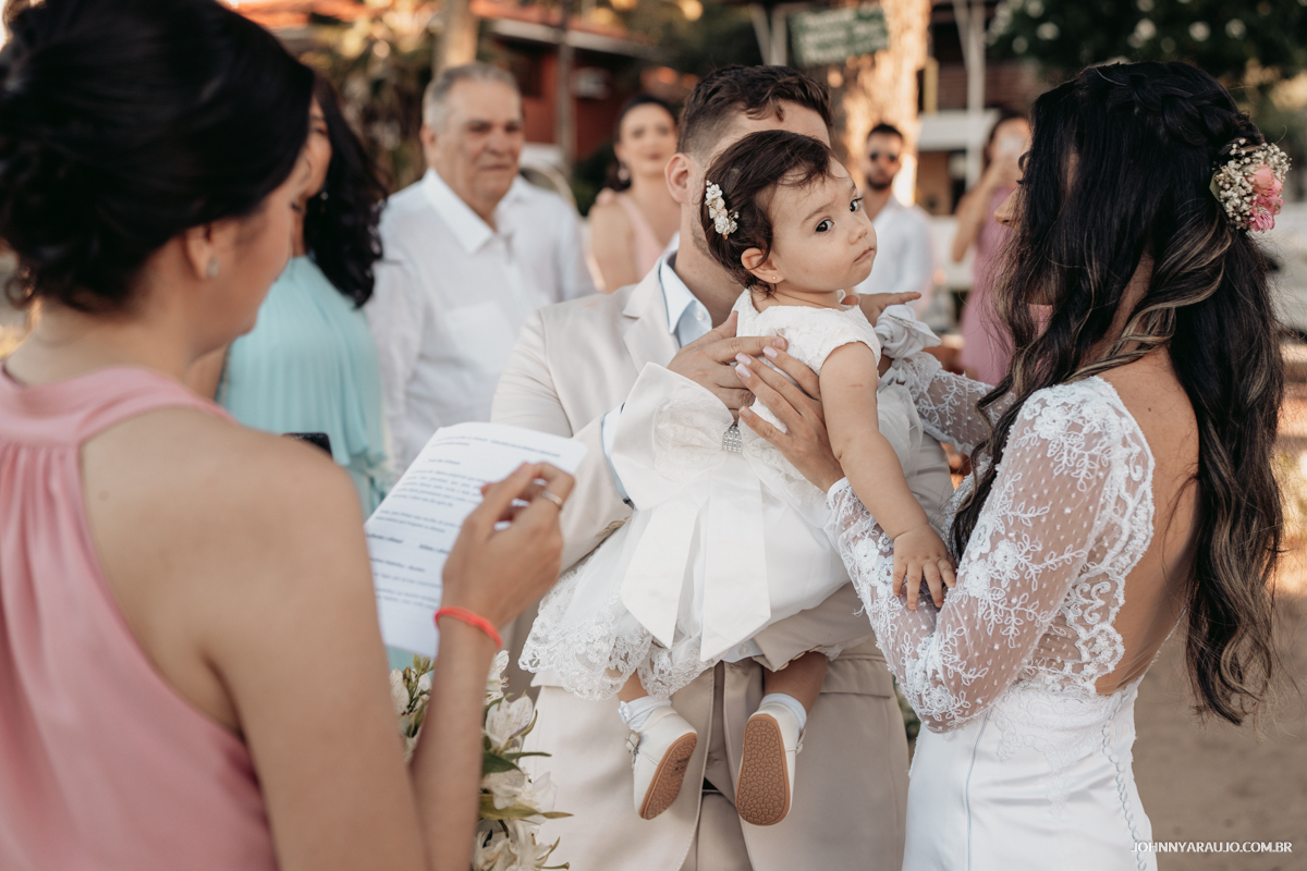 Noivos que já são pais. casaram na praia e sua filha de um ano leva as alianças até o altar