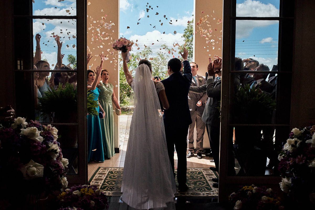 noivos saindo da igreja, flores sendo jogadas, noivos felizes, casamento de dia
