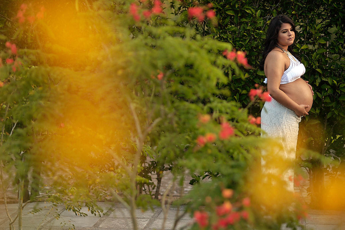 mãe encostada numa parede de folhas