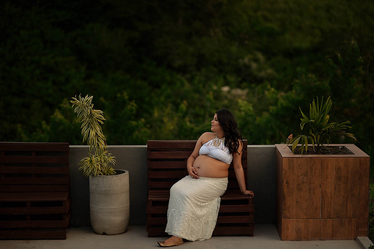 mãe sentada com folhagens verdes ao fundo