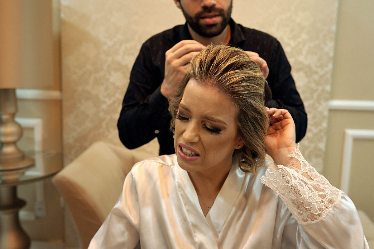 casamento de larissa e thiago por 4Mãos fotografias, noiva no making of sentindo dor arrumando o cabelo
