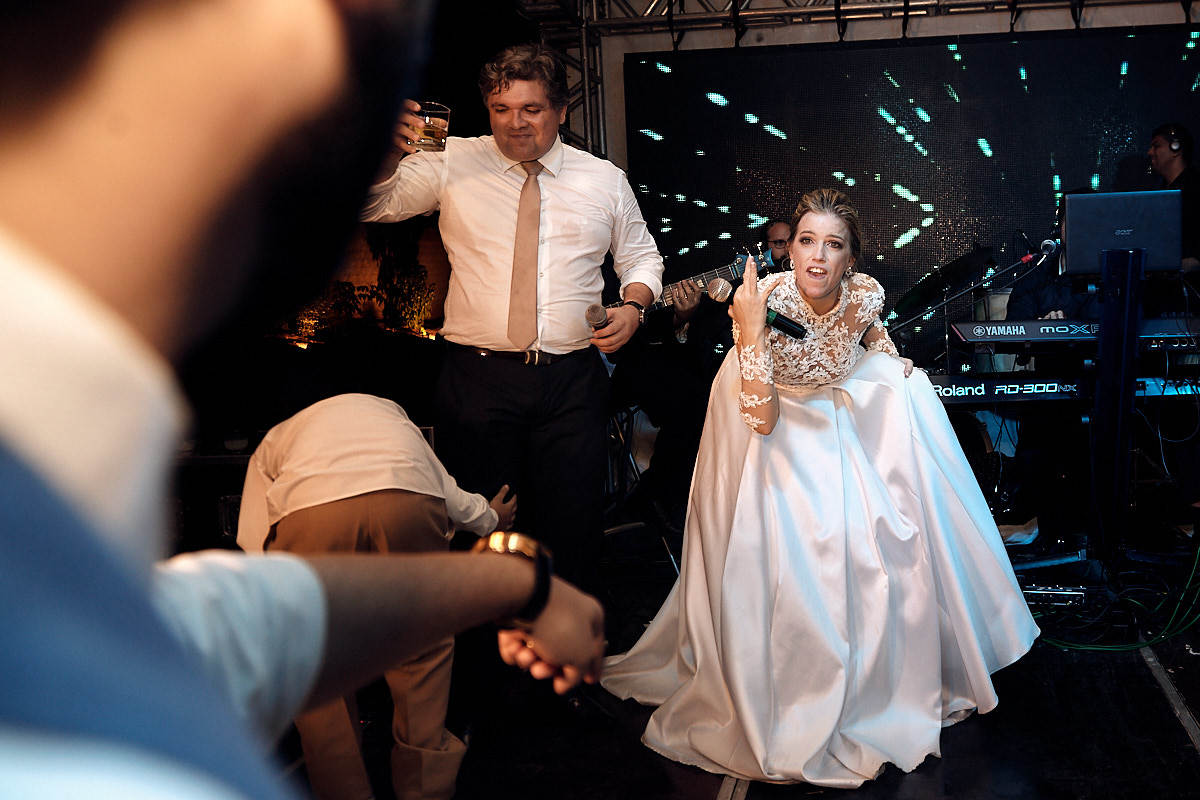 casamento de larissa e thiago por 4Mãos fotografias, convidados se divertindo, noiva no palco chamando o noivo
