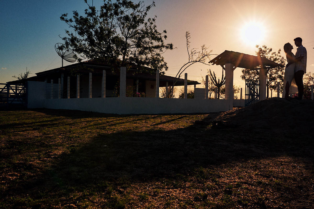 ensaio de Fernanda e Lucas em Catolé de Boa Vista no sitio do sua avó, casa ao fundo, silhueta, casal se olhando
