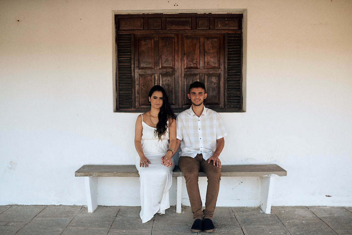 ensaio de Fernanda e Lucas em Catolé de Boa Vista no sitio do sua avó, casal sentado no banquinho em frente a janela
