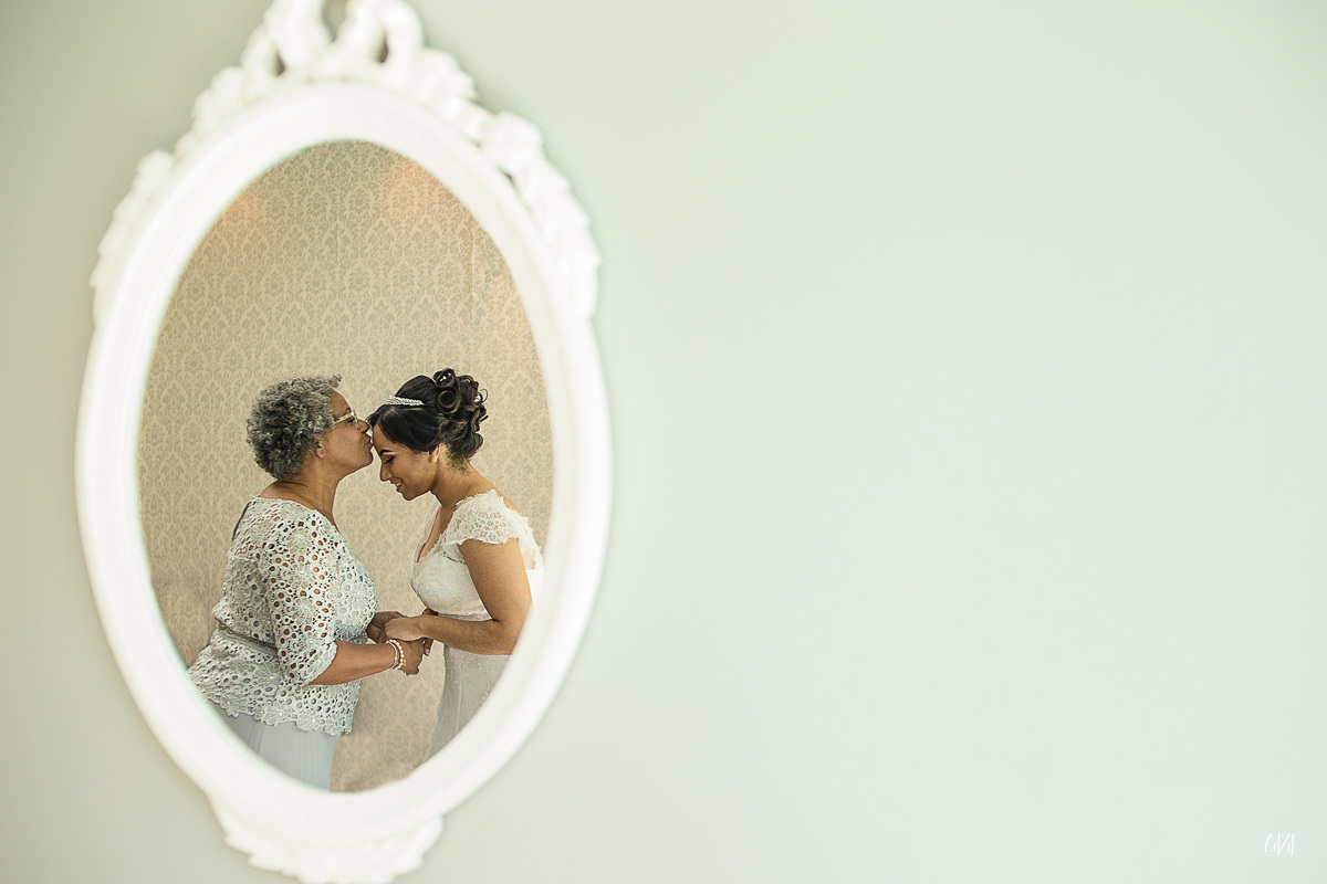 Fotografia de casamento dia da noiva com mãe beijando e espelho