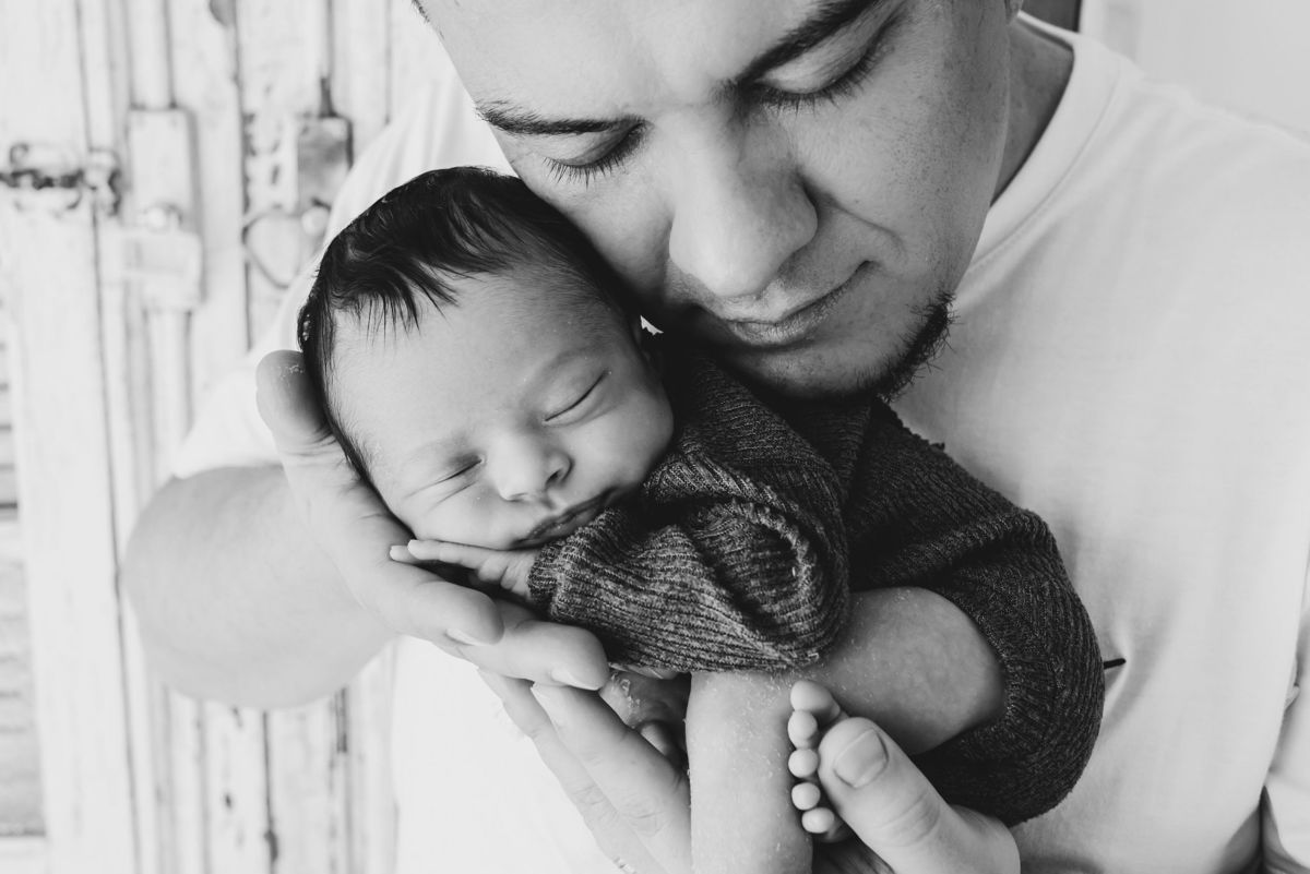 pai segurando seu bebe em foto preto e branco