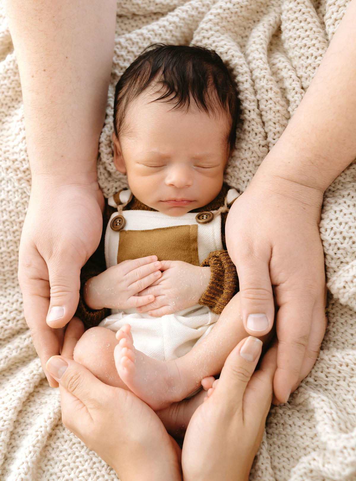 bebe recem nascido com mãos do pai em volta