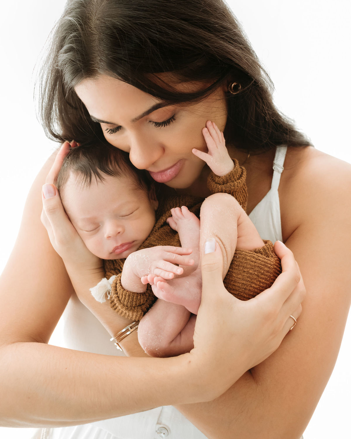 mamãe segurando seu bebe enquanto ele coloca mão no rosto dela