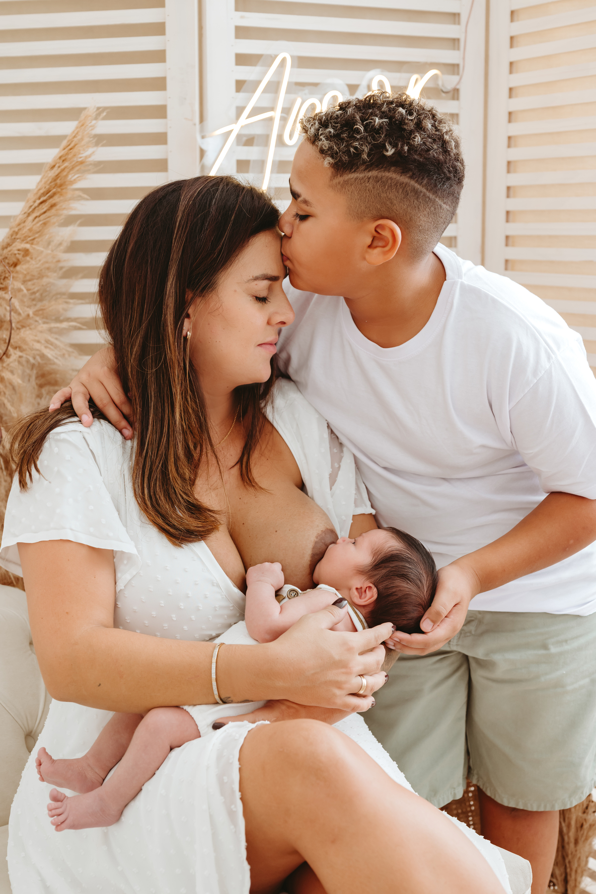 mãe morena amamentando seu filho. criança grande de 8 anos em pé e bebe no colo