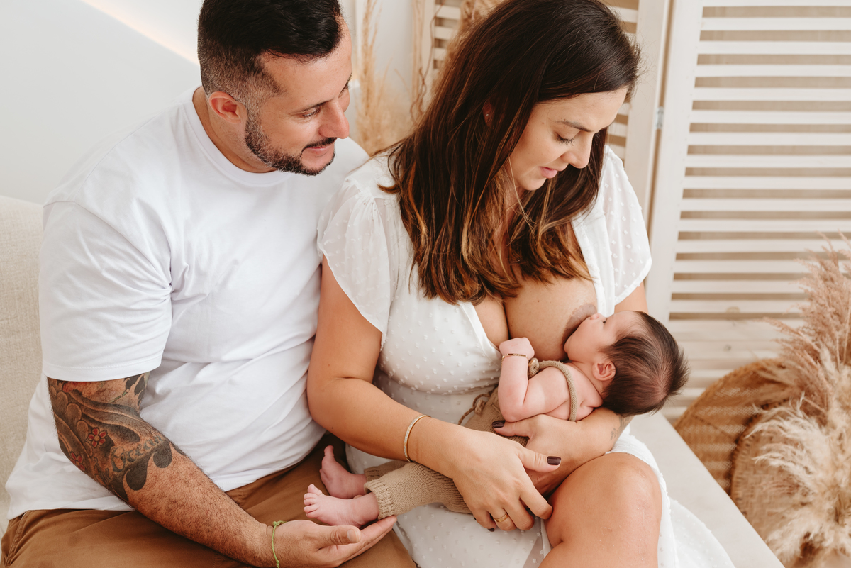 casal moreno sentado. mãe amamentando seu bebe