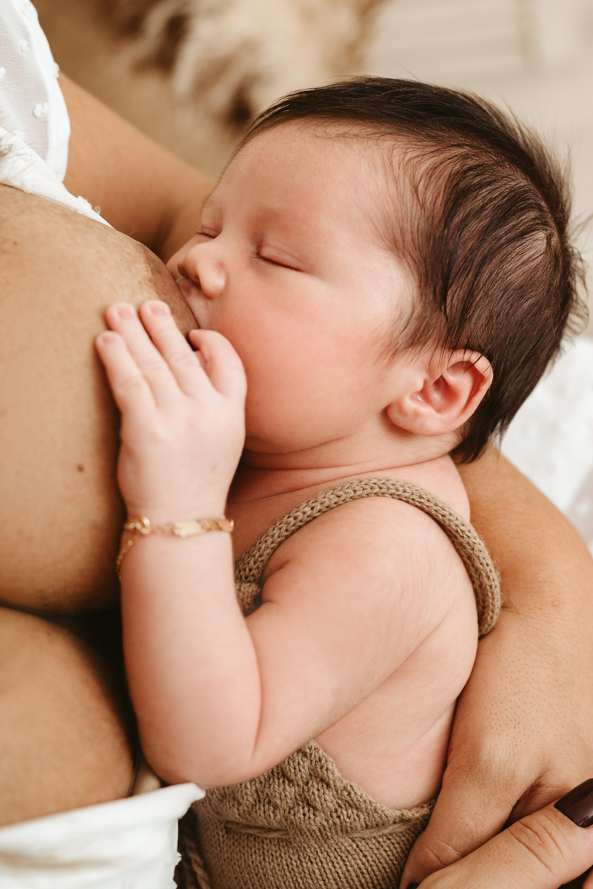 Bebe mamando. detalhe focado na pulseira escrito: Leonardo