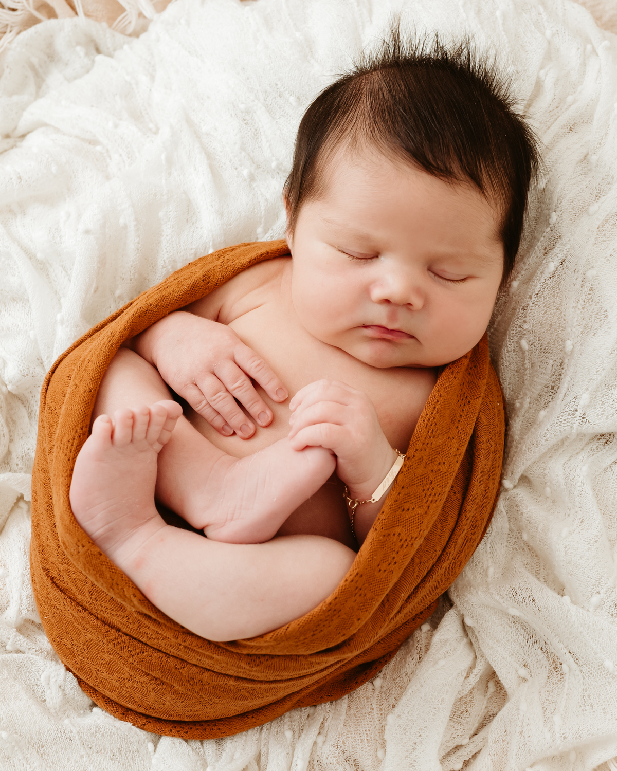 bebe recém nascido enroladinho em pano de cor marrom