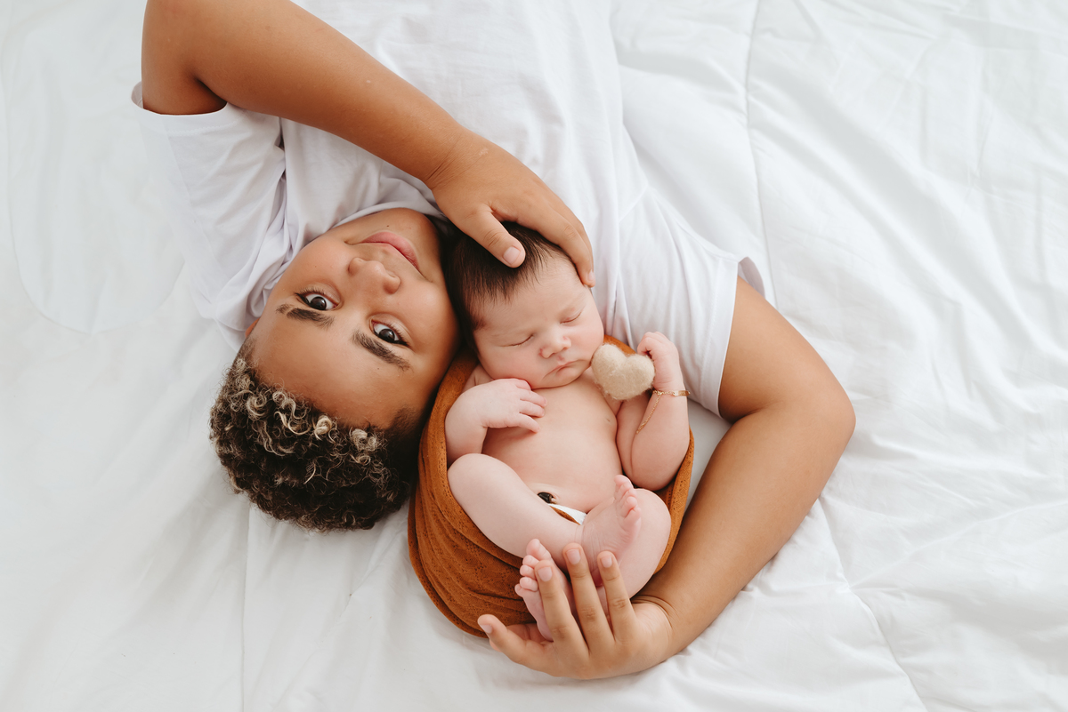 irmãos em foto feita de cima. filho mais velho segurando seu irmão recém nascido