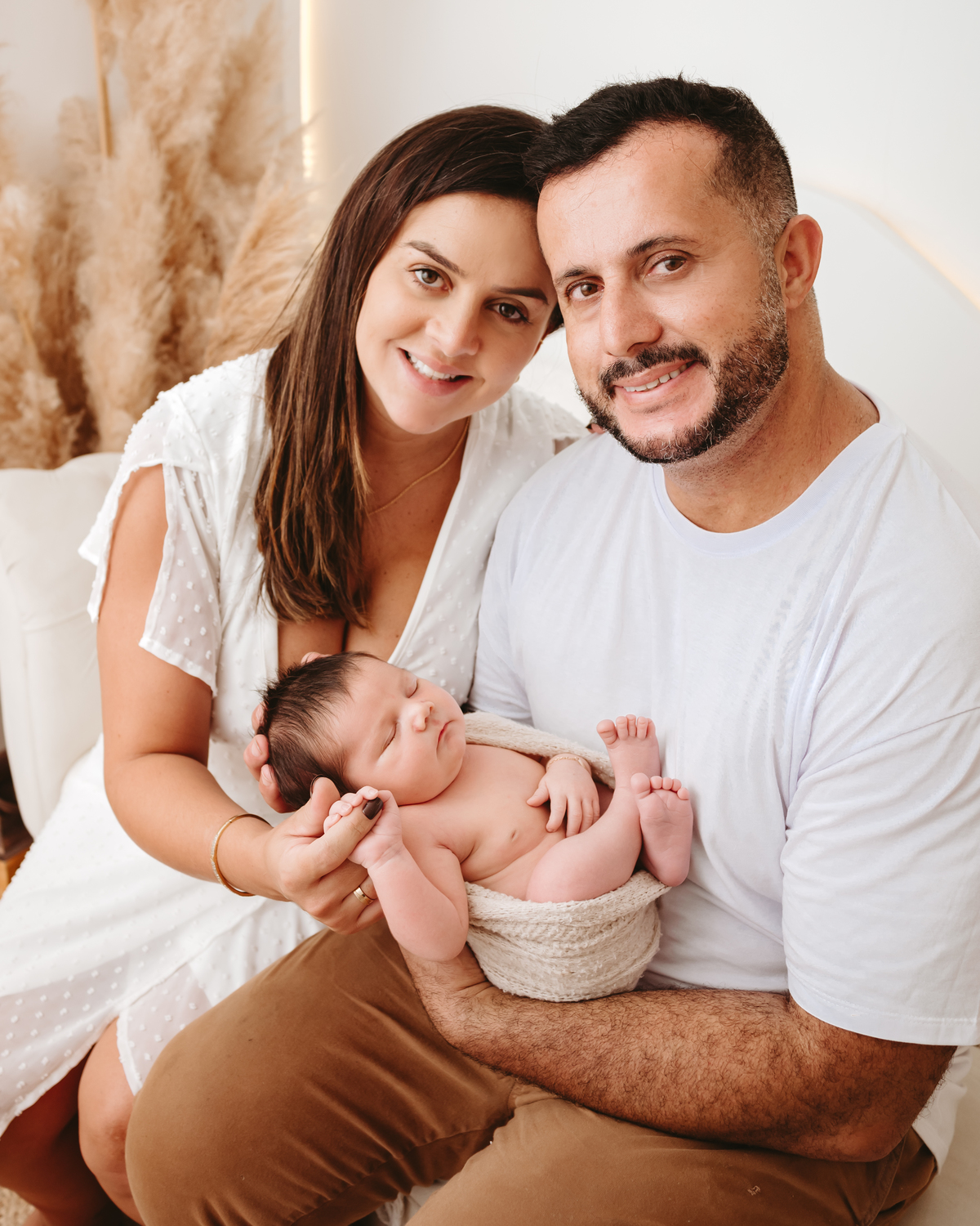 mãe, pai e filho de cor olhando para a câmera. bebe enroladinho