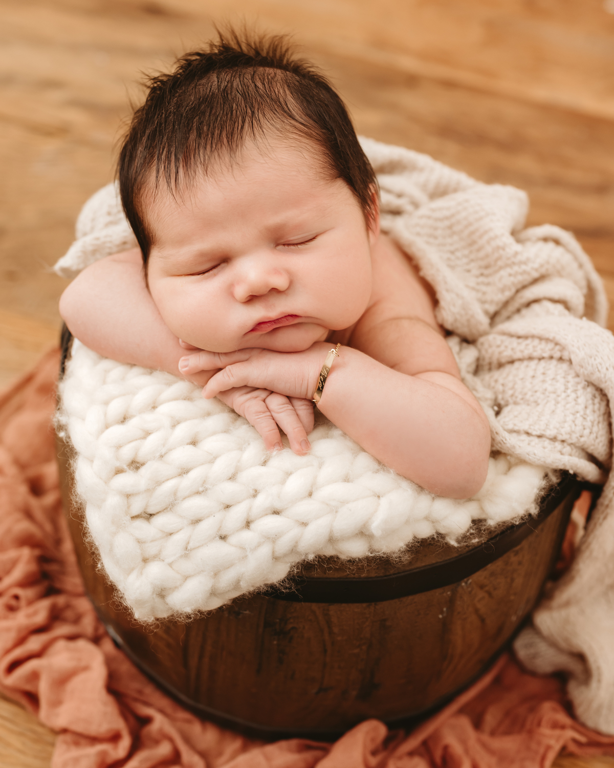 bebe dentro de um baldinho com bracinhos segurando na bora