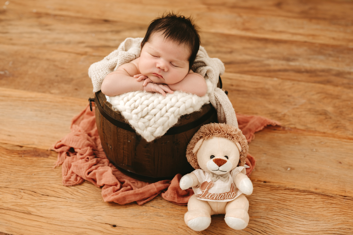 recém nascido dentro de um baldinho com bracinhos na borda