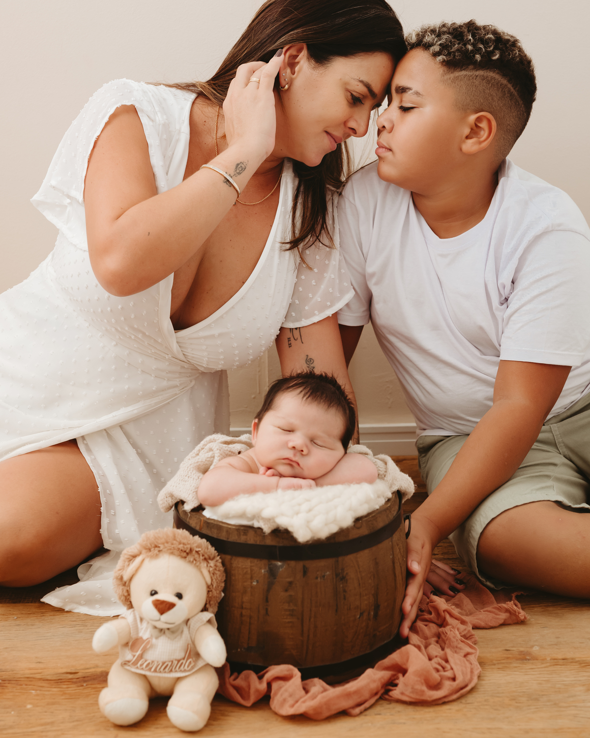 mãe, filho mais velho e bebe. bebe recém nascido em uma baldinho e filho e mãe com nariz junto
