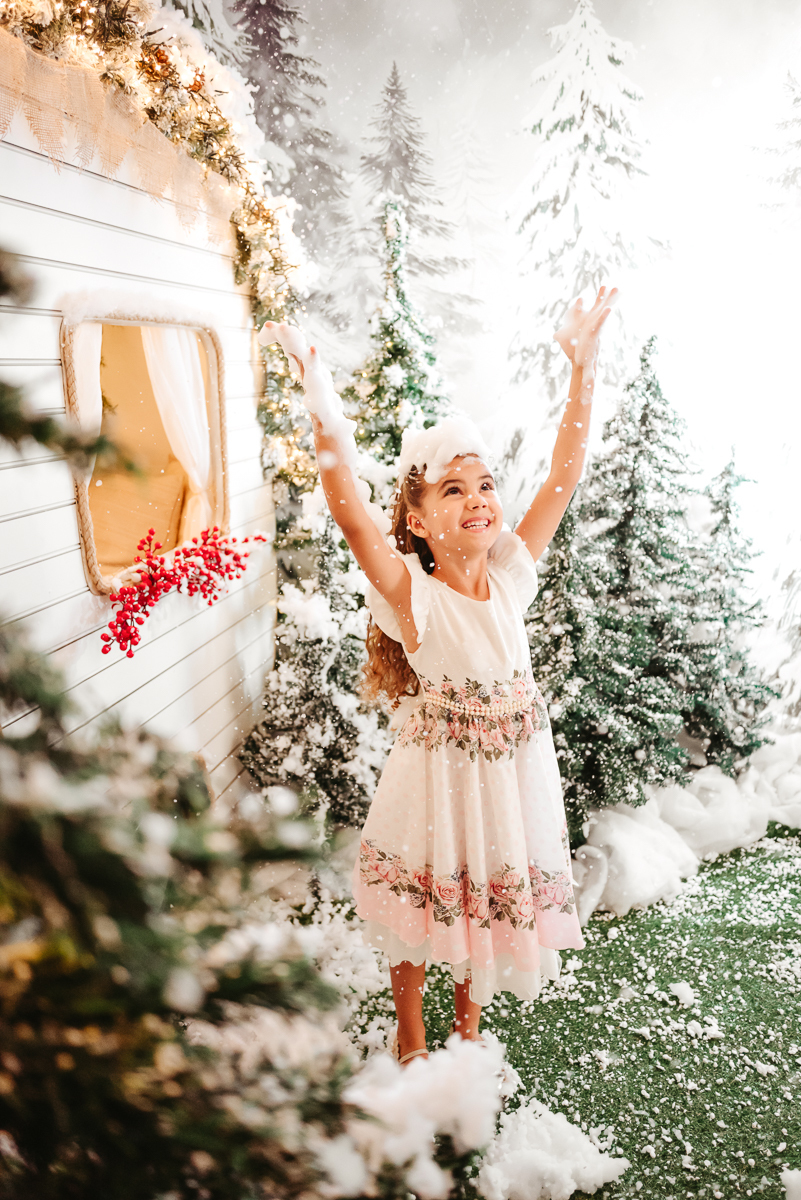 menina com braços projetados para cima se divertido ao sentir a neve cair sobre ela