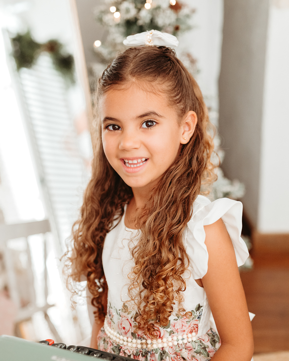 menina de cabelos longos e cacheados em cenário claro e minimalista