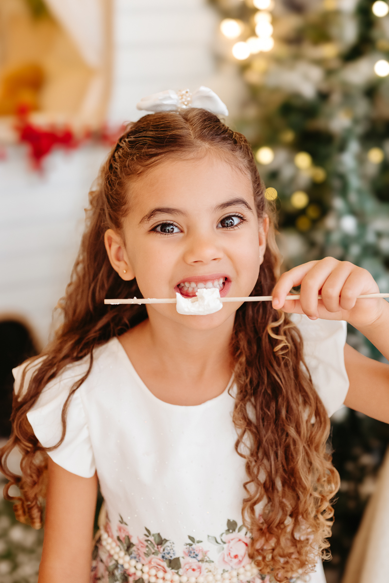 menina abocanhando marshamllow em cenário de natal