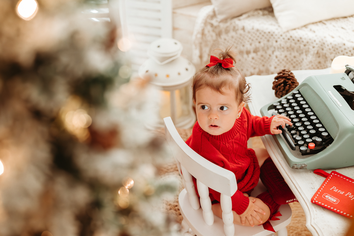 menina sentada em cadeira infantil com mãos em uma máquina de escrever antiga