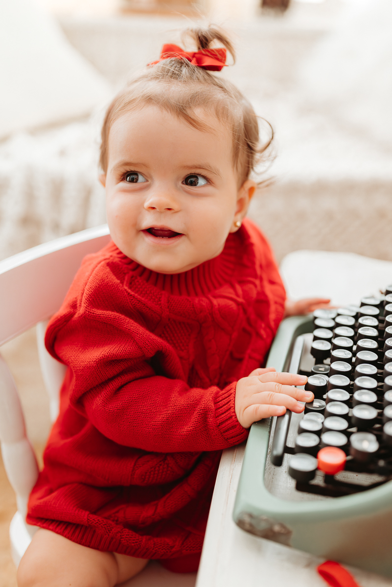 menina brincando com máquina de escreve antiga. a bebe tem aproximadamente 8 meses