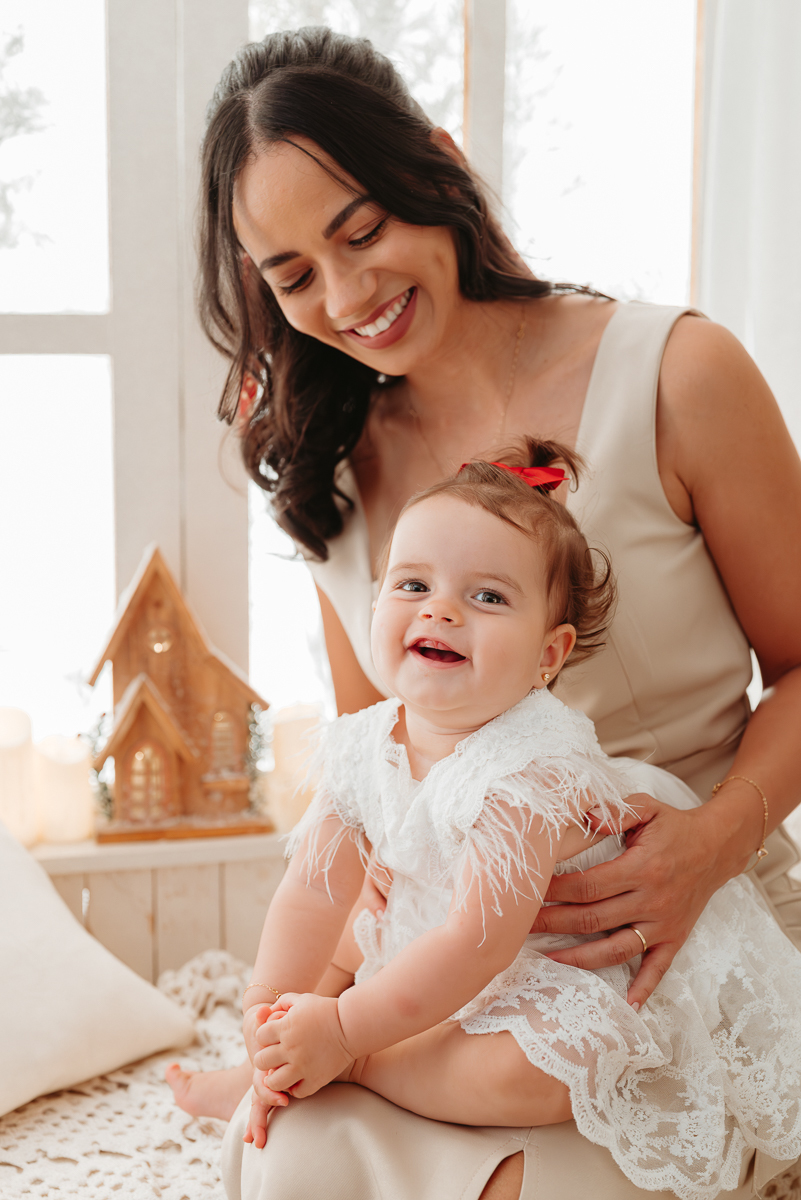 mãe e filha em cenário de natal clean com janela branca