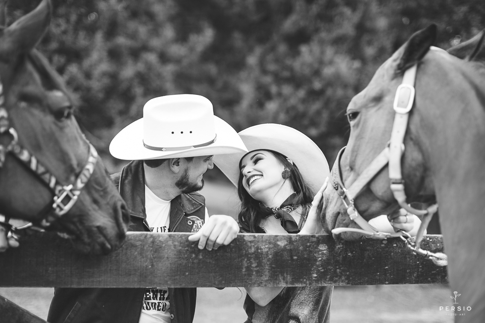 casal se olhando fazendo fotos com cavalos na chacara capela das graças em araucaria parana ensaio com os fotografos persio photo art fotografia em preto e branco