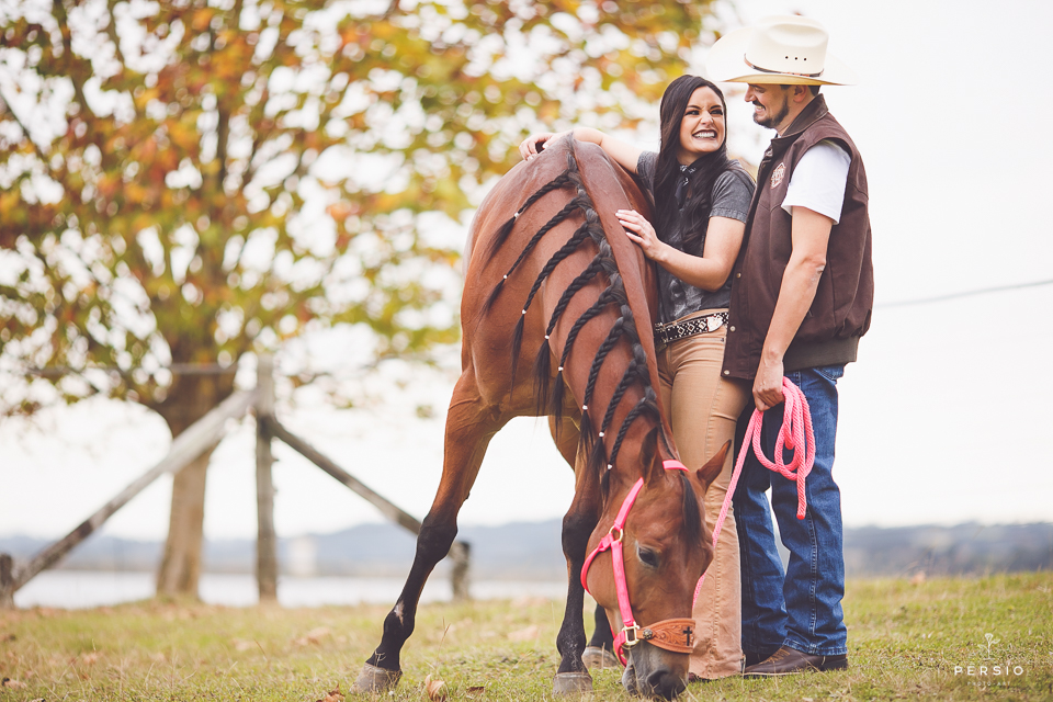 casal se olhando fazendo fotos de ensaio pre wedding com cavalos bota e chapéu na chacara capela das graças em araucaria parana ensaio com os fotografos persio photo art