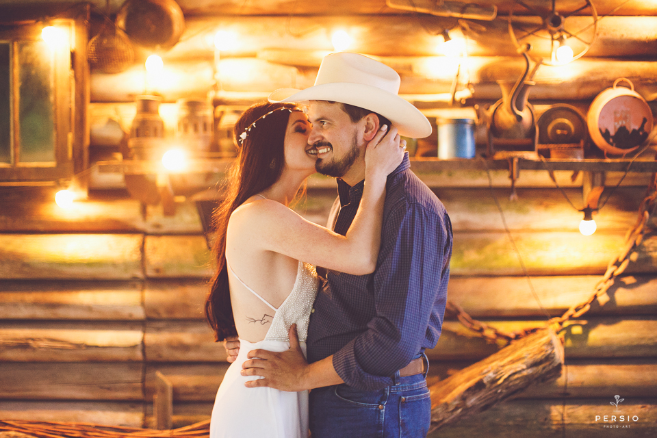 casal se olhando fazendo fotos com cavalos na chacara capela das graças em araucaria parana ensaio com os fotografos persio photo art ensaio de casal com bota e chapéu fotografo curitiba