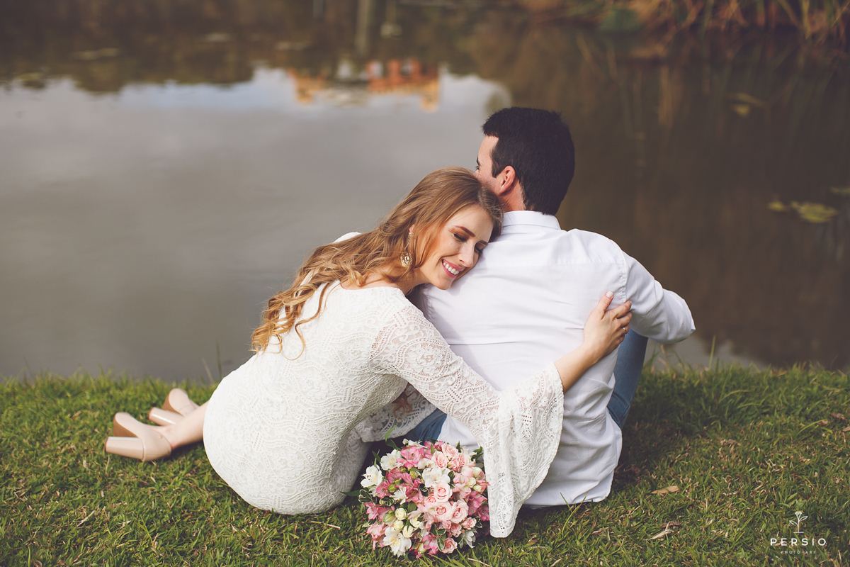 casal sentado ao lado do lago do parque tangua em curitiba abraçados e com sentimento de amor fotografados por persio photo art