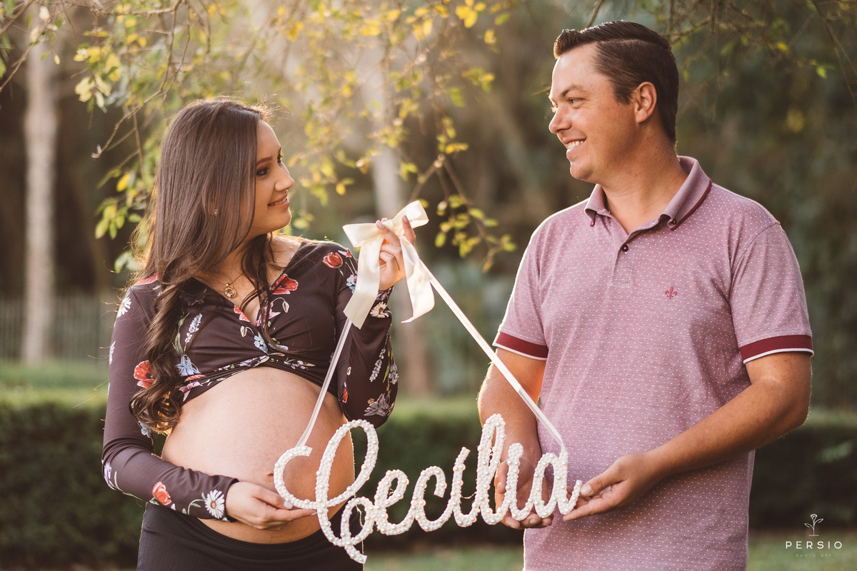 casal segurando a plaquinha com o nome do bebe no ensaio de gestante no bosque alemão