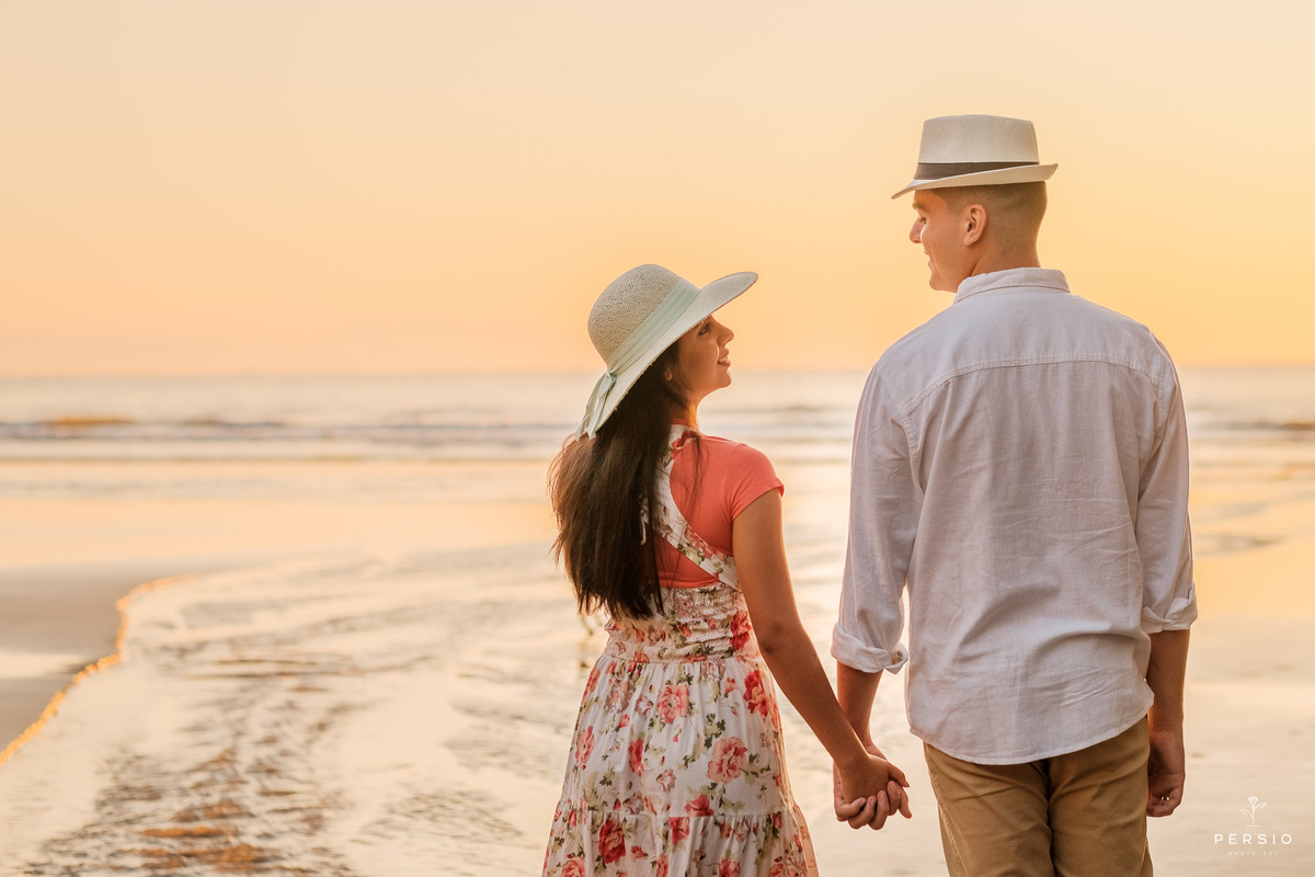 casal de chapéu na praia ao nascer do sol