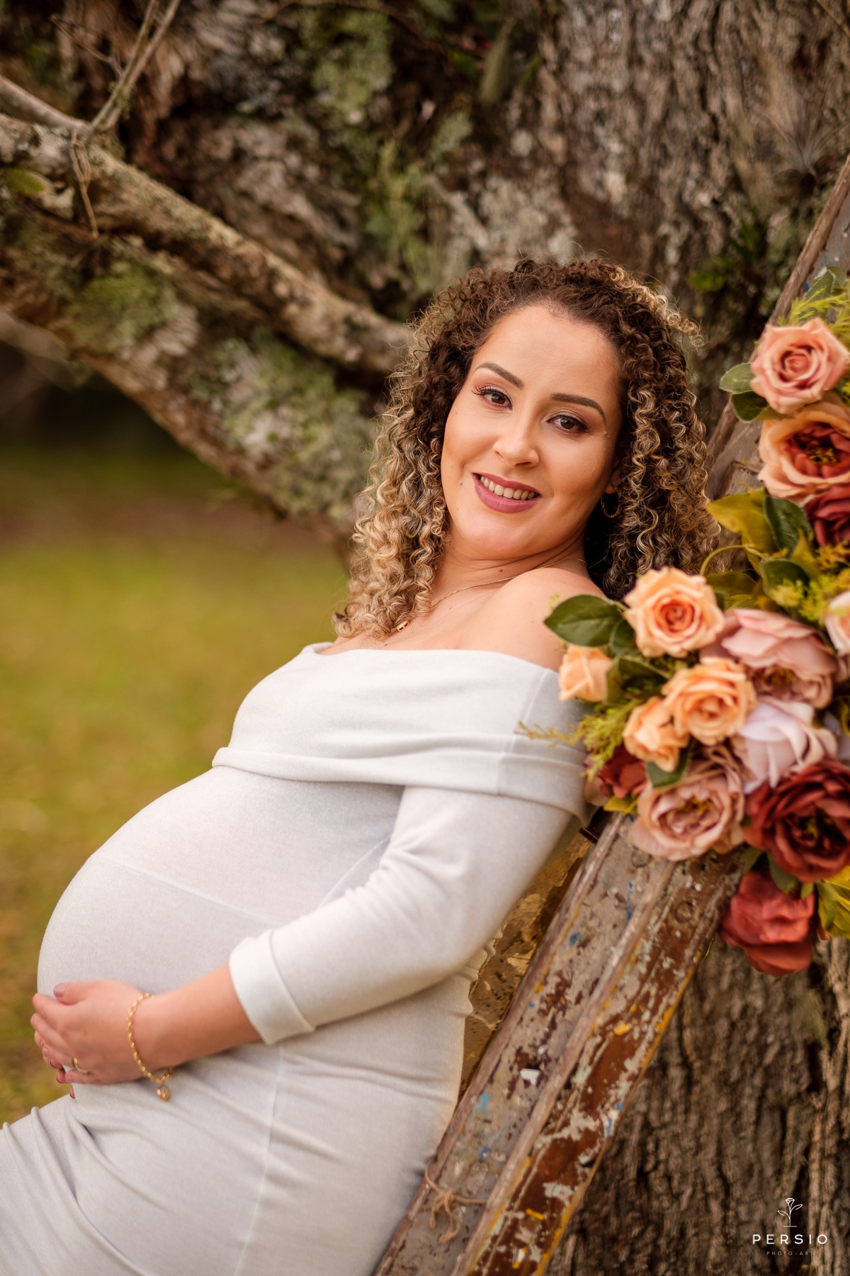 grávida com vestido cinza prata apoiada em uma escada decorada com flores