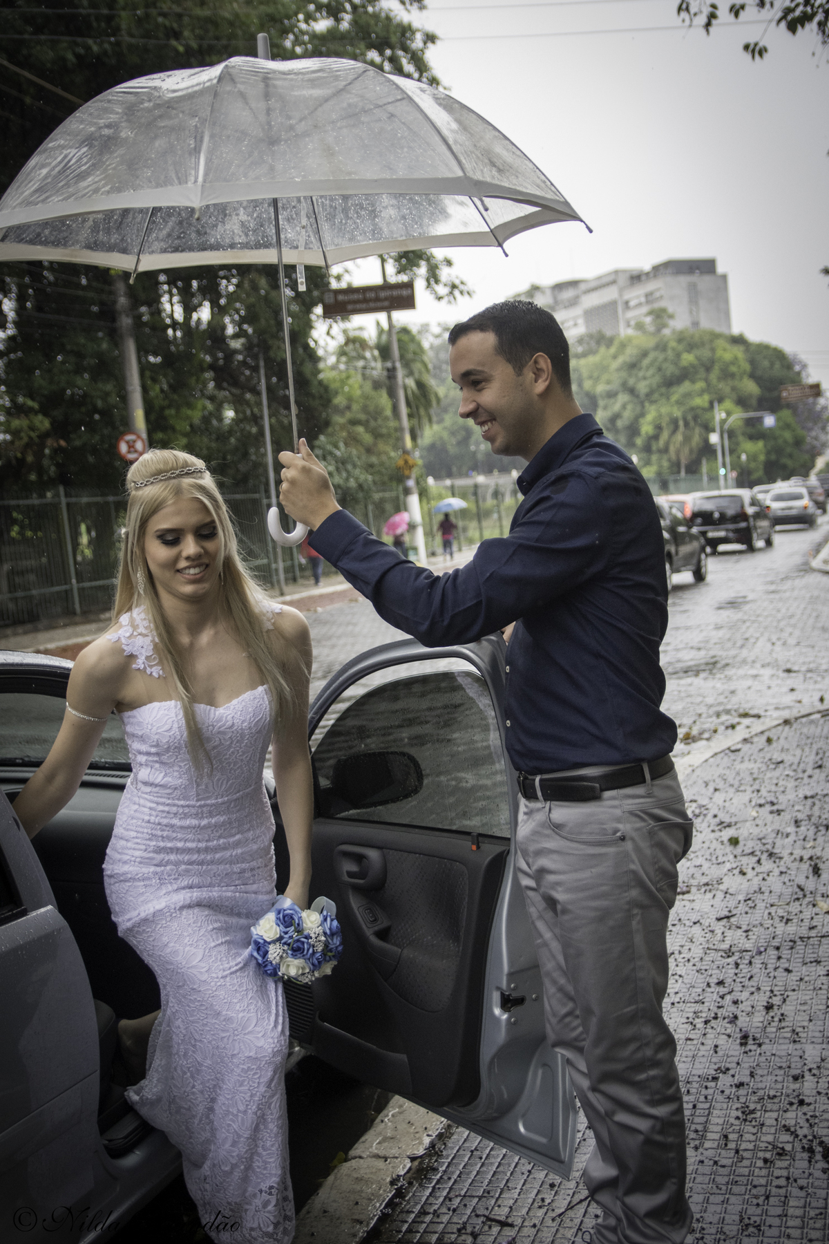 O cavalheirismo ainda não morreu, que bom! Noivo segura o guarda chuva para noiva sair do carro, e abriu a porta para ela antes. 