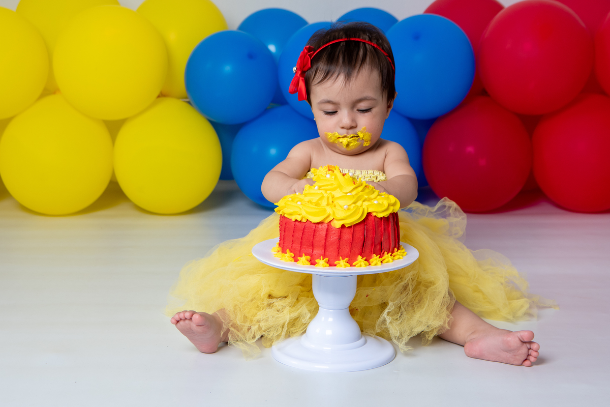 Smash the cake com fotos lúdicas no tema Branca de Neve, primeiro fazemos as fotos lúdicas, depois as fotos do banho de do bolo, enriquecendo ainda mais o primeiro ano da bebê