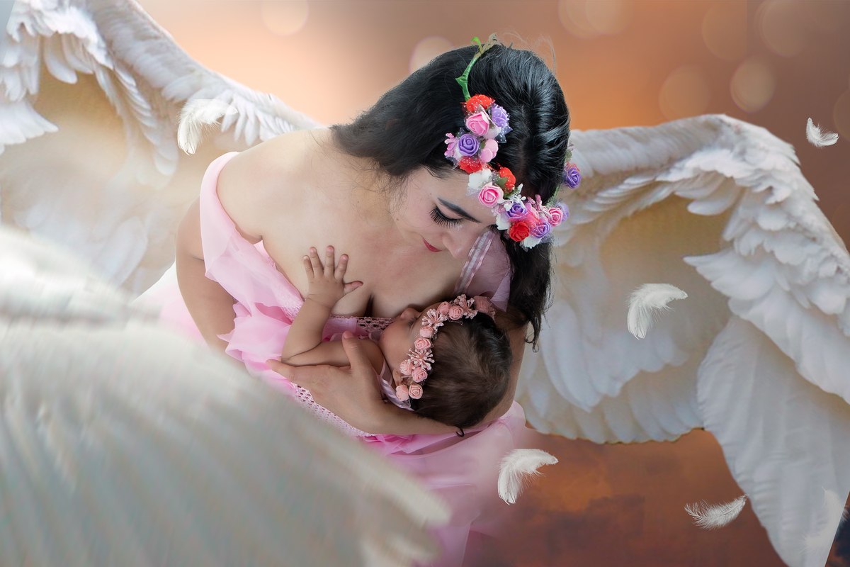 Ensaio fotográfico lúdico com tema Jardim encantado, mãe segurando a filha com asas de anjo 